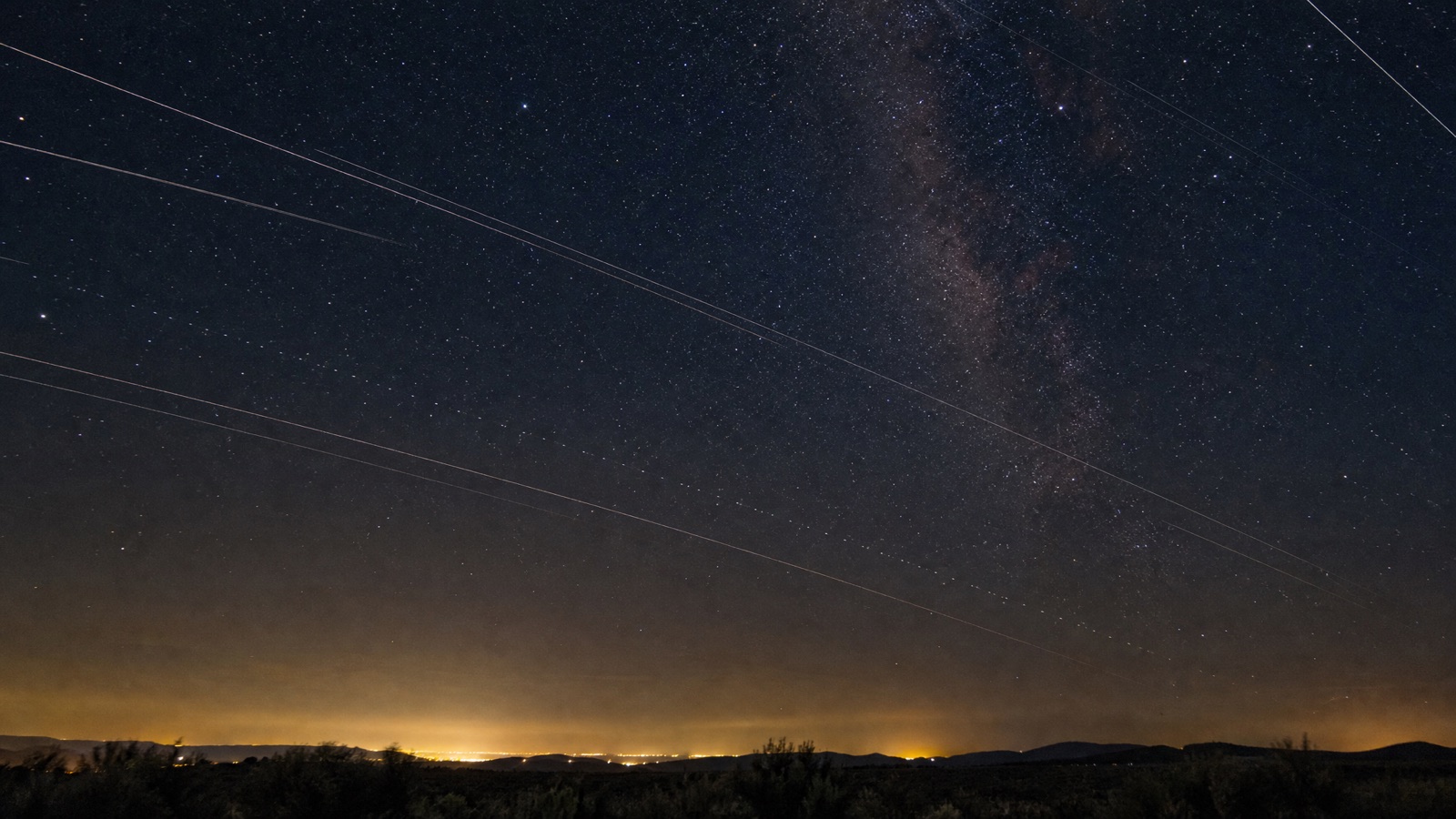 Long-exposure night sky photograph showing satellite trails streaking across the stars